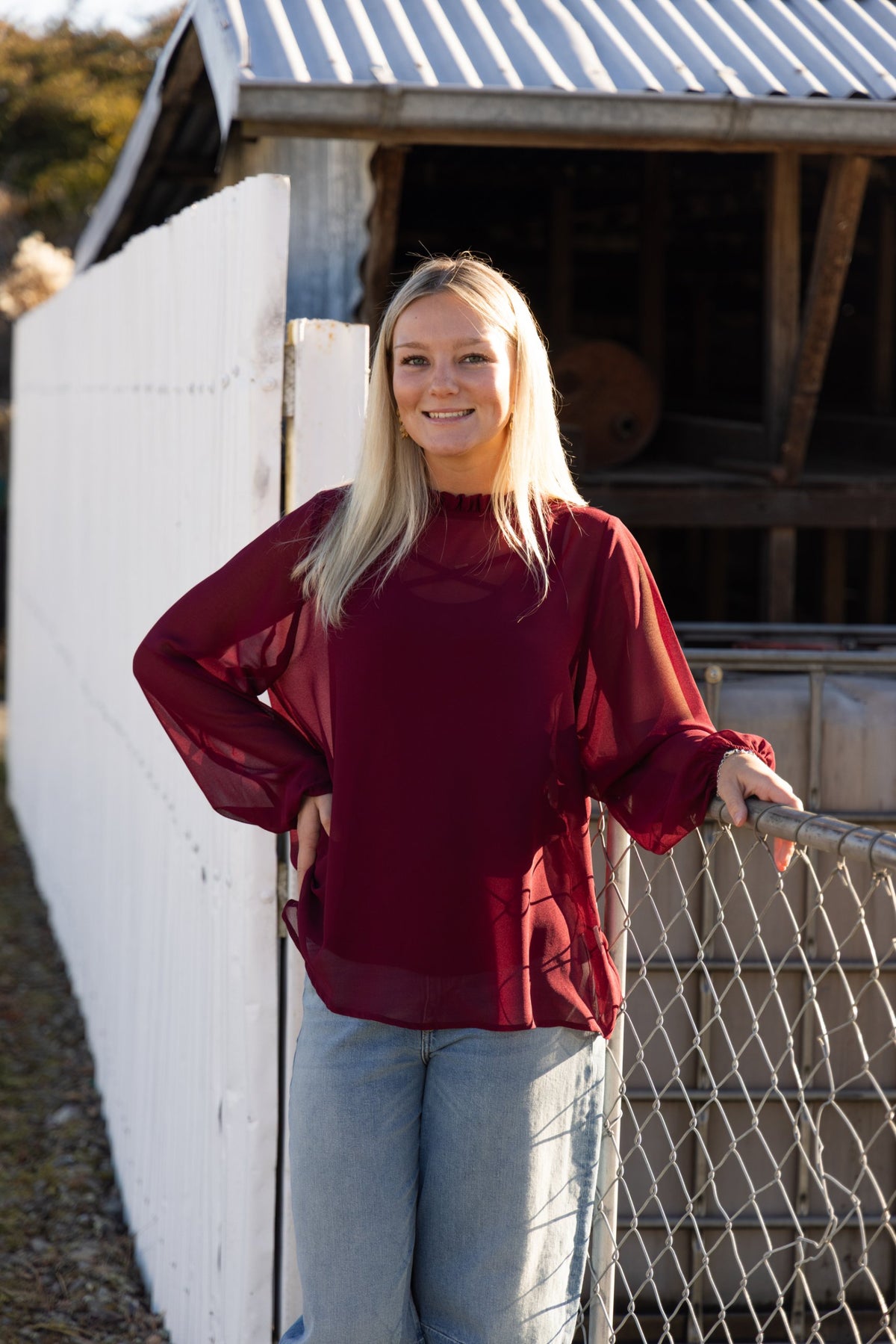 Blank Space Label burgundy chiffon top with a frilled high neck, worn with light wash jeans
